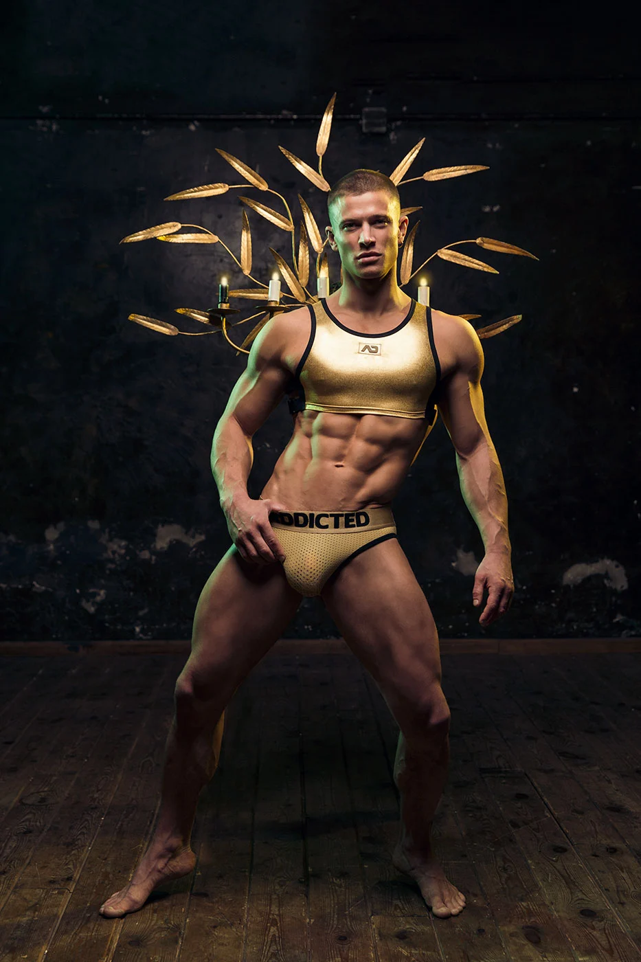 A model in a black and gold harness posed under a dramatic gold headdress