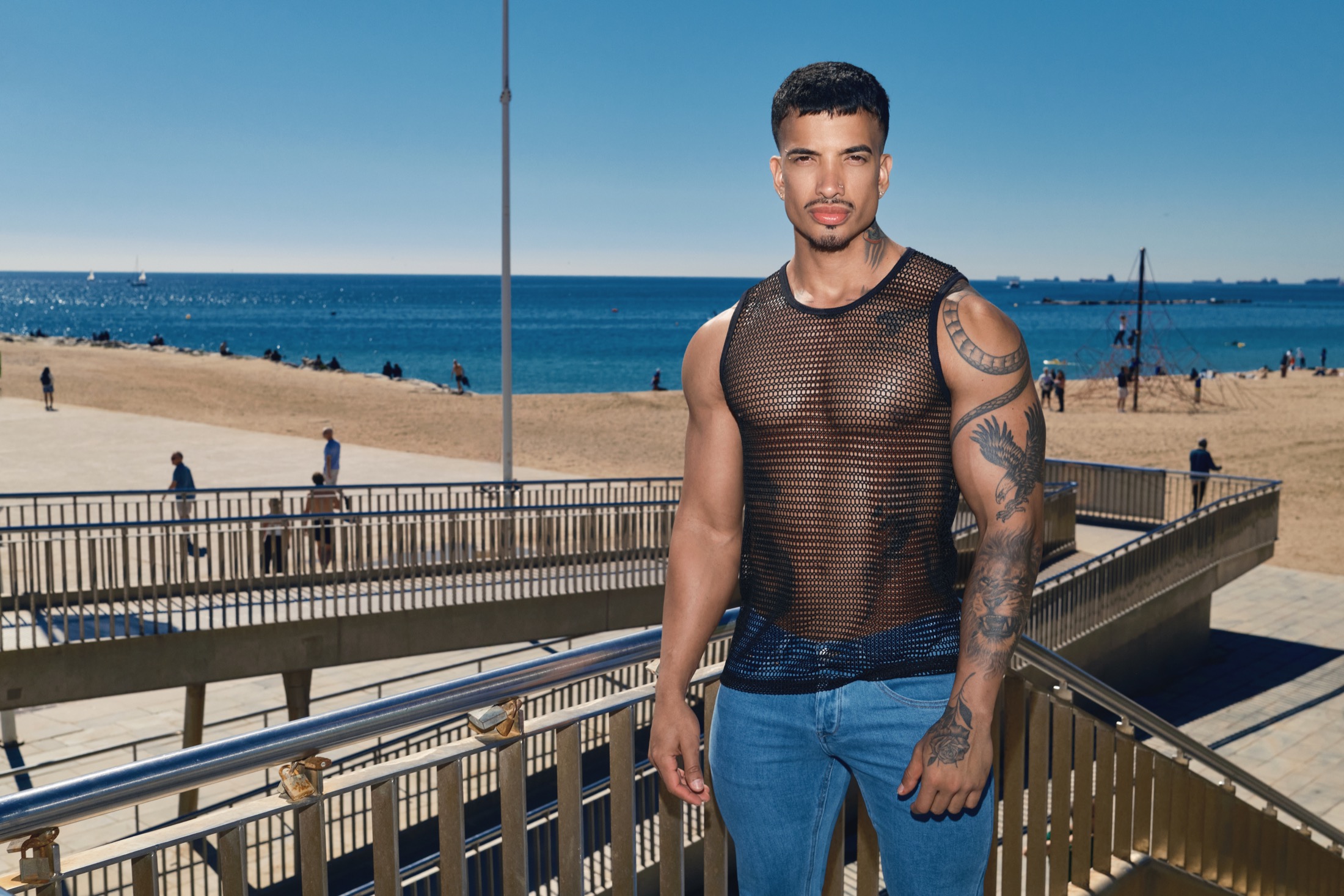 Model in a black ADDICTED mesh tank top and jeans by the beach in Barcelona