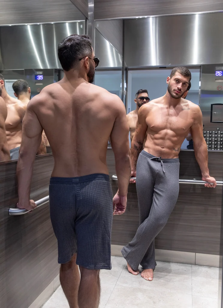 Two ES Collection models reflected in a lift mirror wearing dark casual looks