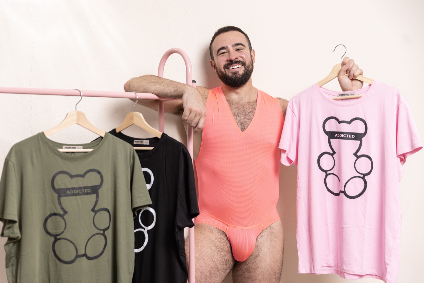 Modell élénk pink bodyban, mellette háromszínű ADDICTED medvés pólóválogatás