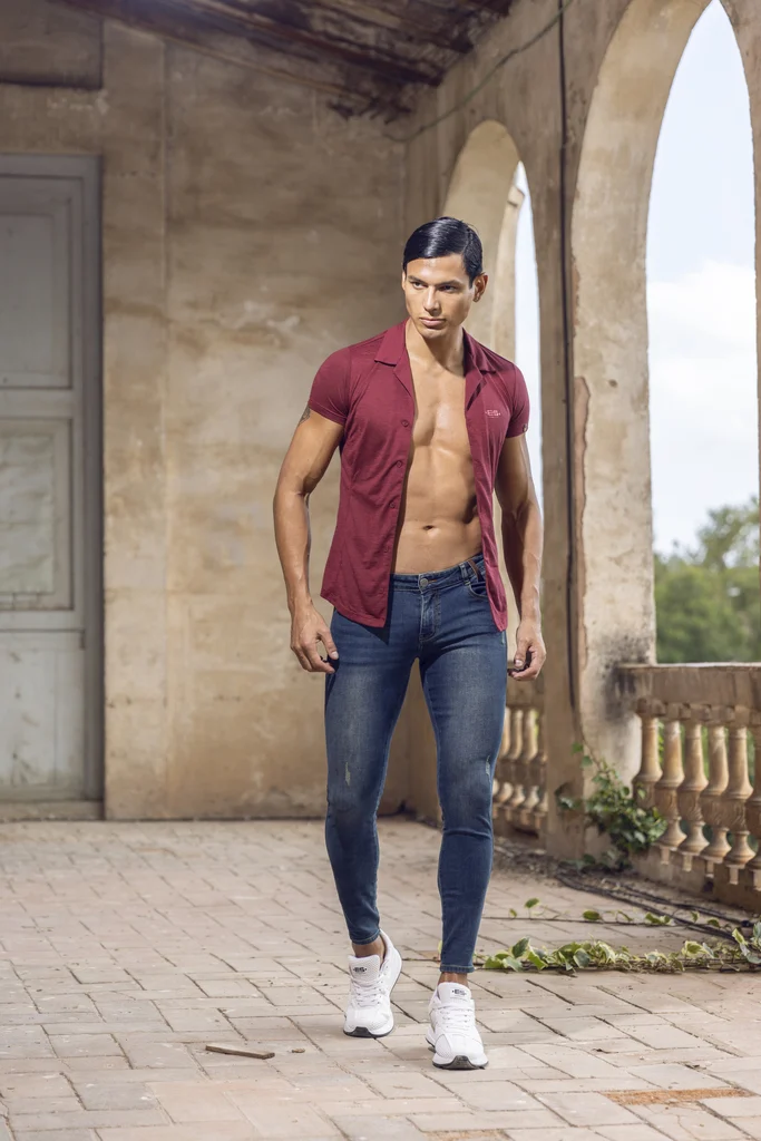 ES Collection model in a burgundy shirt and dark trousers beneath stone arches