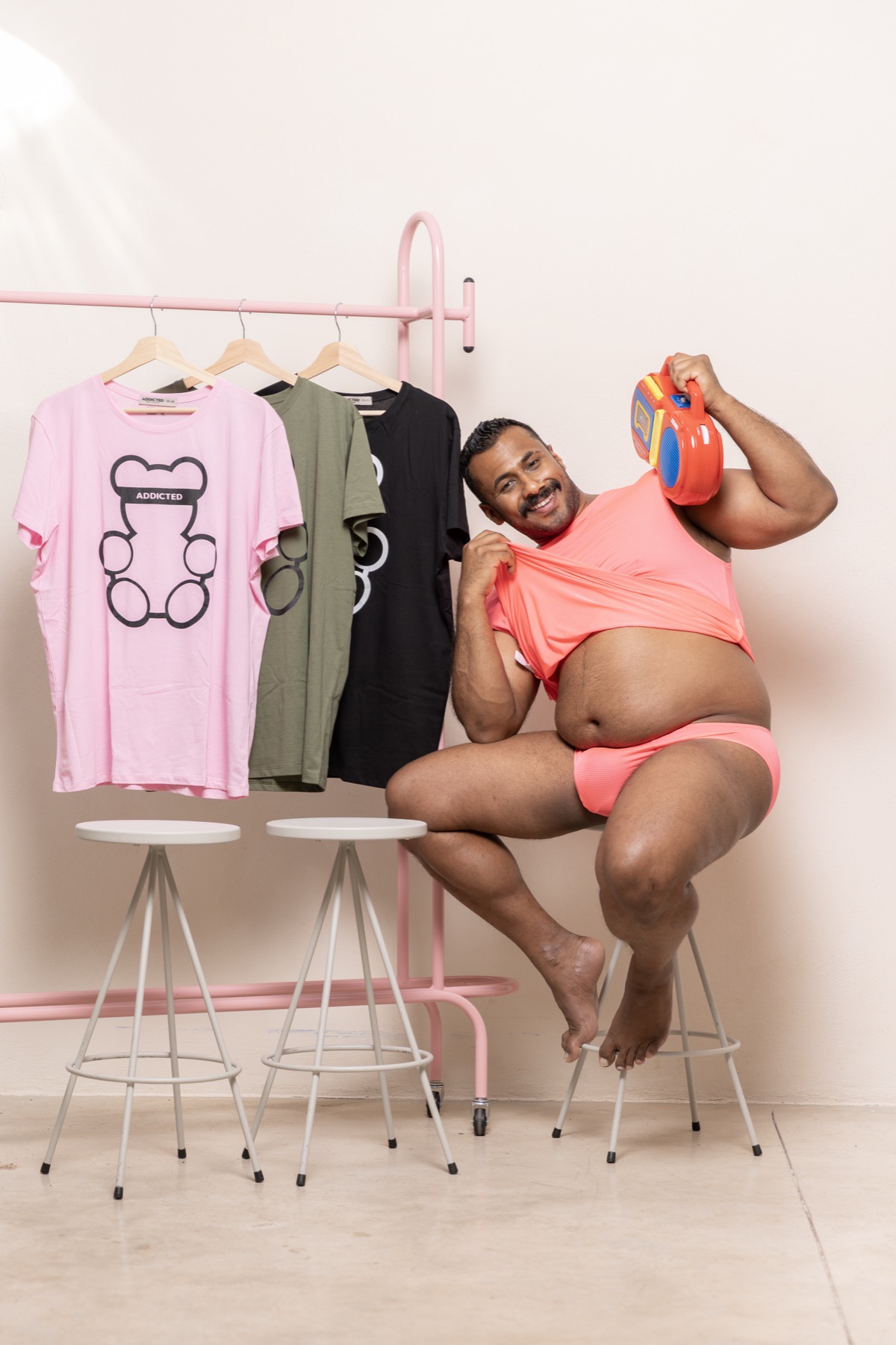 Modell pink ADDICTED ruhában, mellette medvés mintájú pólók