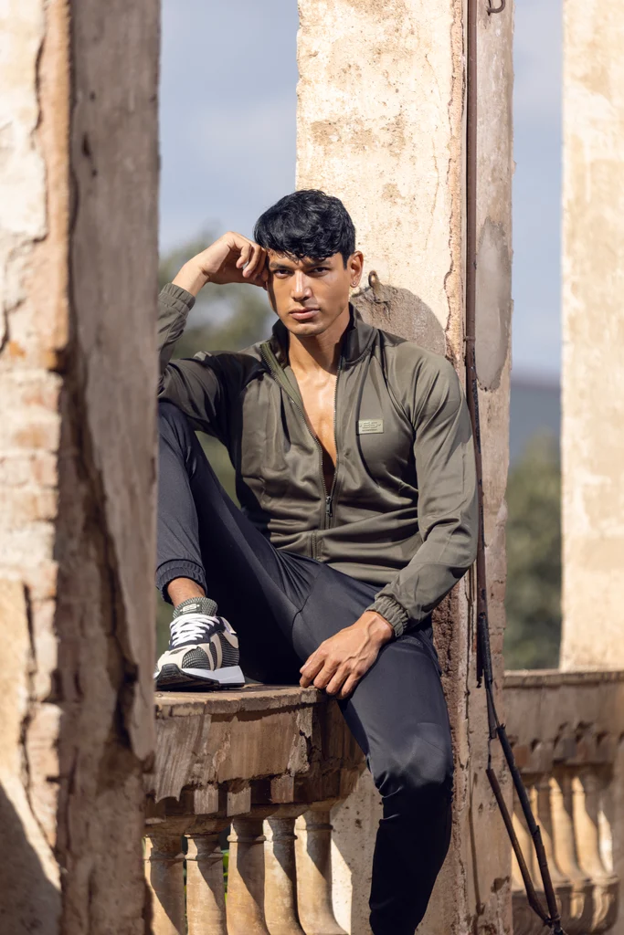 ES Collection model wearing an olive jacket and dark casual layers on a stone terrace