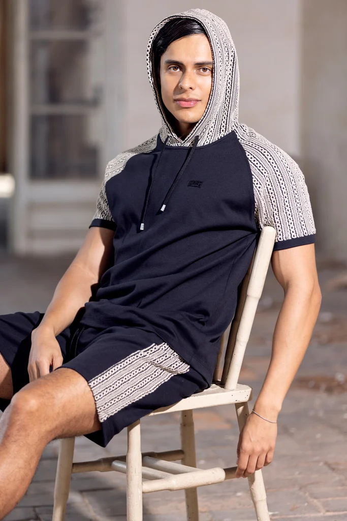 ES Collection model wearing a hooded navy sports look in a stone courtyard